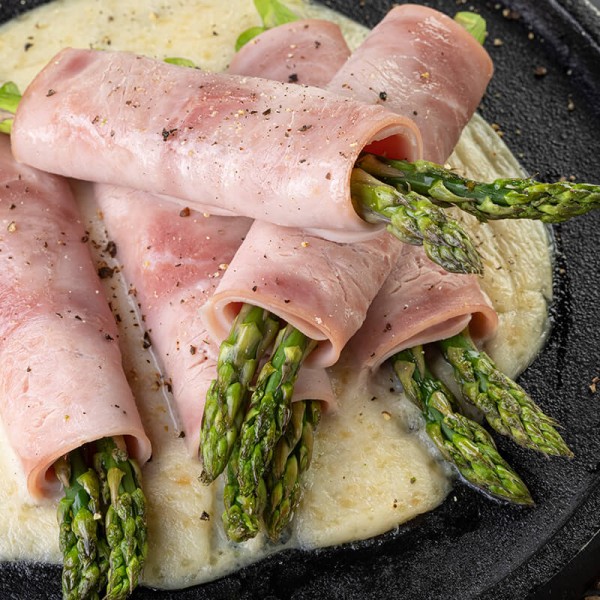 Esparragos envueltos en Jamón y salsa de queso parmesano.